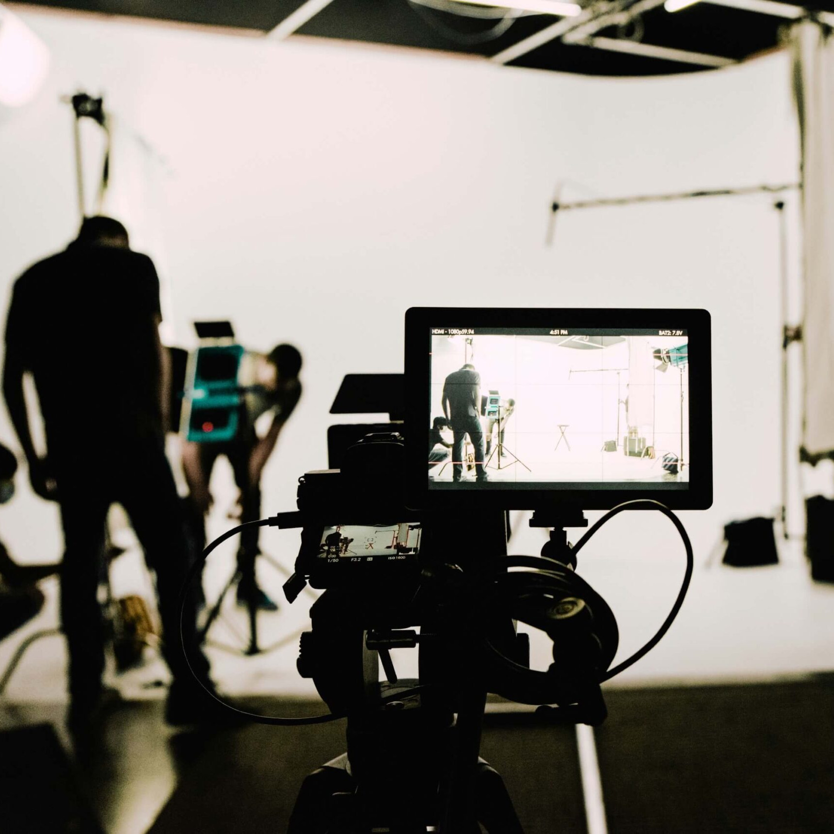 Caméra professionnelle filmant une scène en studio avec une équipe technique en arrière-plan lors d’une captation vidéo.