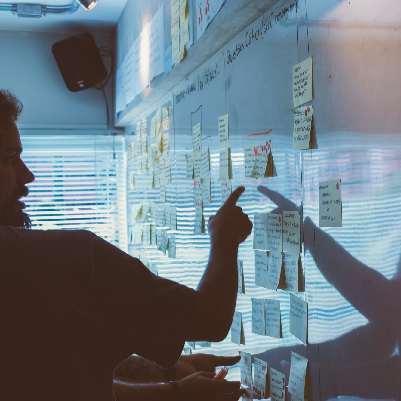 Professionnel organisant des notes autocollantes sur un mur pour planifier les étapes d’un projet de tournage.